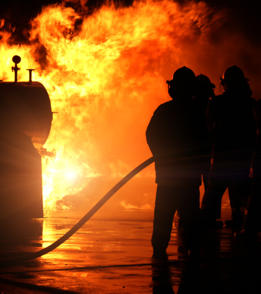 An industrial fire rages at night as firefighters try to keep it contained.
