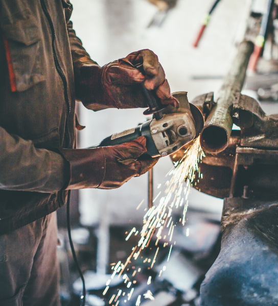 Worker using a hand saw in a plant, sending sparks from metal