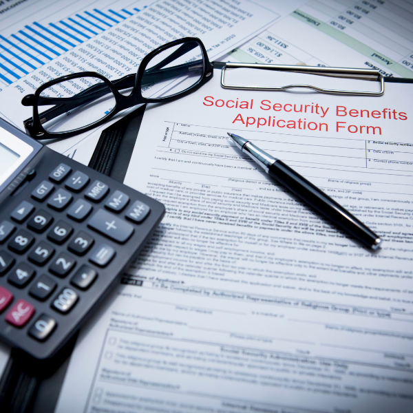social security benefits application form near glasses, a calculator, and a pen