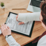 brown haired male with arm cast filling out a workers compensation form