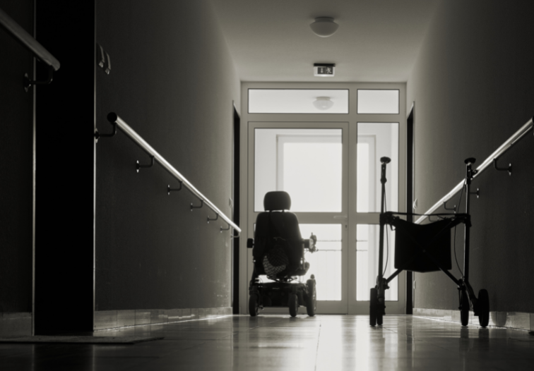 Empty wheelchair in dark hallway in nursing home