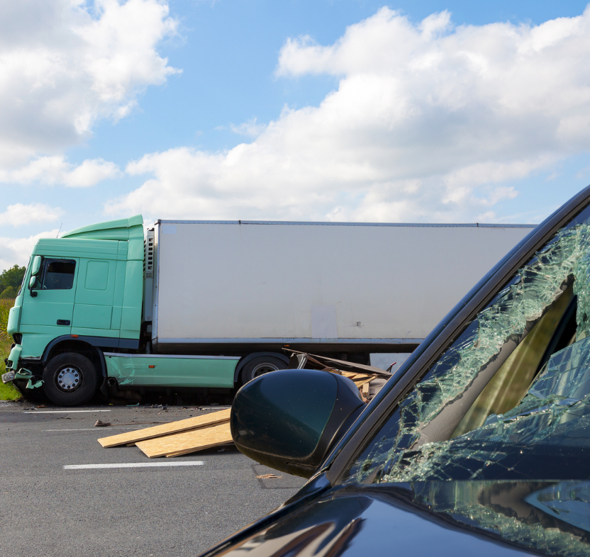 An 18-wheeler and a car with a smashed windsheild by the side of the road after an accident