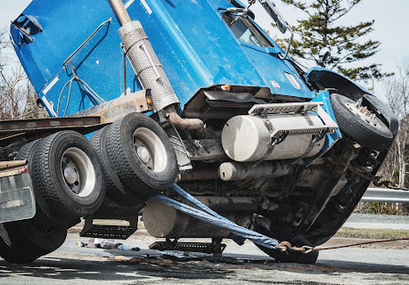 Gran camión azul siendo enderezado por una grúa después de un accidente en Gonzales, LA