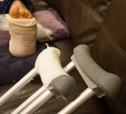 Crutches and a foot in a cast resting on a couch.