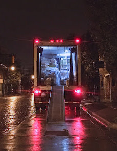 A delivery truck unloading on the side of a Louisiana street at night.