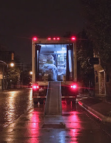 A delivery truck unloading on the side of a Louisiana street at night.