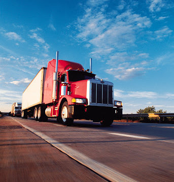 A red and white truck with a high clearance driving down a highway in Louisiana