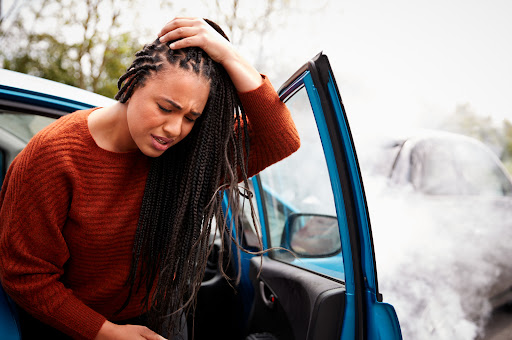 A young woman holds her head in pain after a car accident