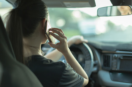 A person drives while holding their phone to their ear, a display of distracted driving in Louisiana.