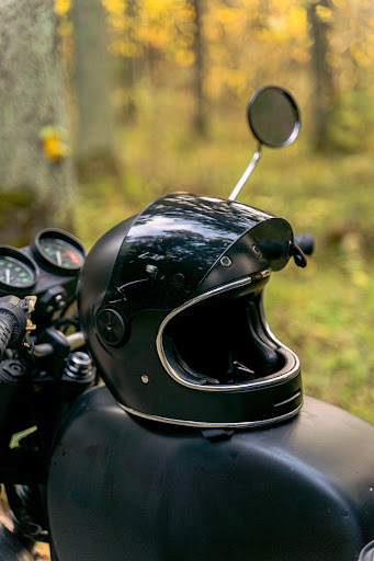 A motorcycle helmet sitting on the seat of a motorcycle in the woods