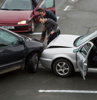 Two men inspecting their damaged cars after a collision