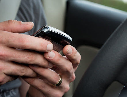 Un primer plano de alguien enviando mensajes de texto al volante de su coche.