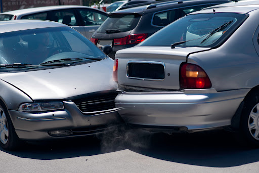 Two silver cars in a parking lot after a minor fender bender accident