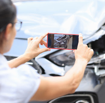 A woman takes a picture of her car damage to send to her Baton Rouge car accident attorney