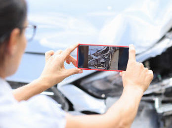 A woman takes a picture of her car damage to send to her Baton Rouge car accident attorney