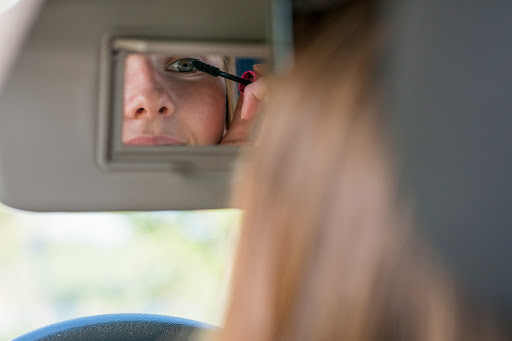 A woman puts on makeup while driving through Louisiana. This is an example of distracted driving.