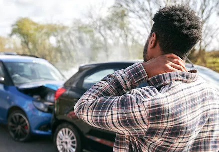 A man holds his neck and surveys the damage after a car wreck in Lake Charles.