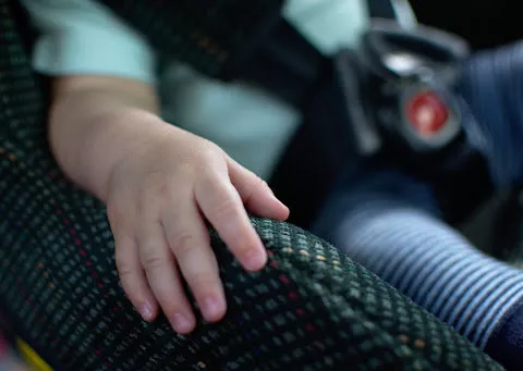 Baby place his hand on the car seat and sit calm. Baby sit in rear facing car seat