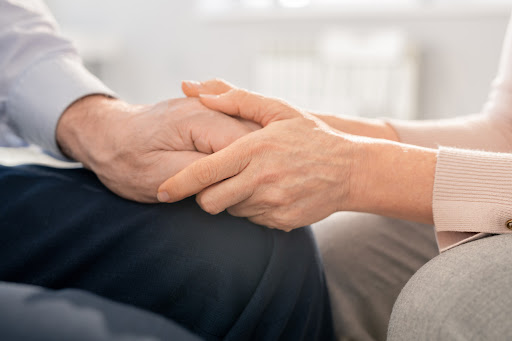 Two elderly people holding hands and comforting each other after the wrongful death of a loved one.