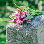 Headstone in cemetery with flowers for concept of death and loss