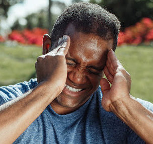 A man touching his temples in pain after suffering a concussion