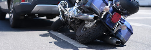 A motorcycle resting on its side behind a car following an accident