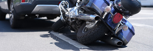 A blue motorcycle lying on its side behind a car after an accident in Alexandria.