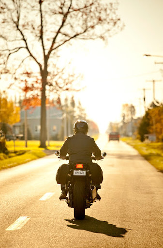 A motorcycle rider cruises down a Shreveport street at sunset