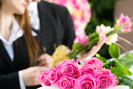 Pink roses on a casket and mourners grieving the loss of a loved one in Monroe, Louisiana.