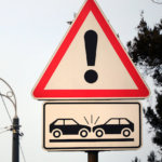 High risk of collision. A road sign with an exclamation point and two cars that crashed into each other