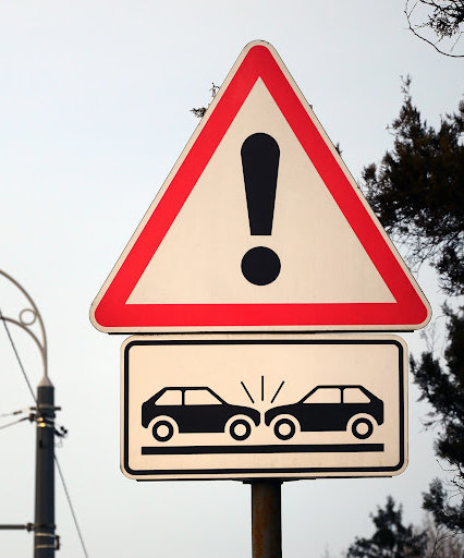 High risk of collision. A road sign with an exclamation point and two cars that crashed into each other