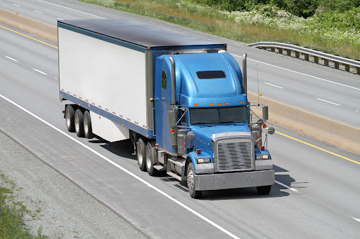 Semi tractor trailer truck hauling a load of freight on a divided highway.