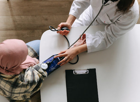 An overhead view of a doctor taking the blood pressure of a cancer patient.