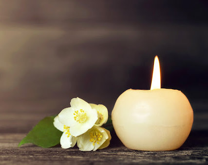 White flower and a single round candle burning as a symbol for the loss of a loved one.