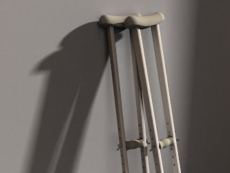 A pair of crutches for those injured in Alexandria lean against a gray wall.