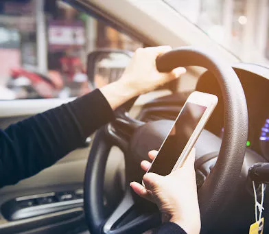 Primer plano de una mujer conduciendo peligrosamente un coche mientras usa el teléfono móvil