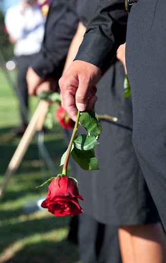 A man holds a single red rose at a funeral of a loved one in Louisiana.