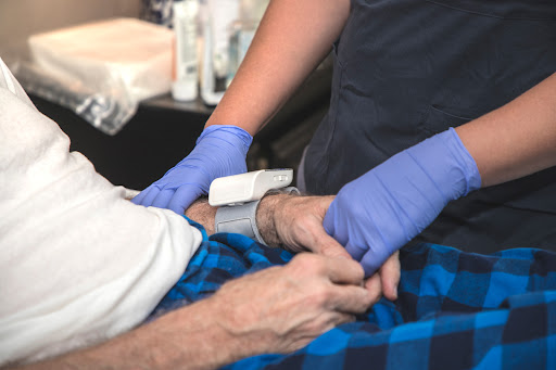 A Parkinson's Disease patient receives care and hold the nurse's hand.