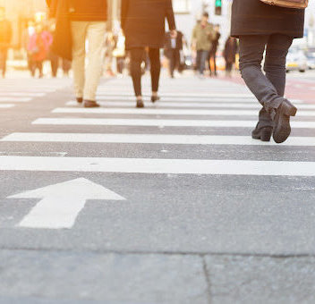 A lot of people are walking on the crosswalk in big city streets in working day.