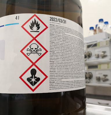 Toxic substance warning labels on the side of a large bottle.