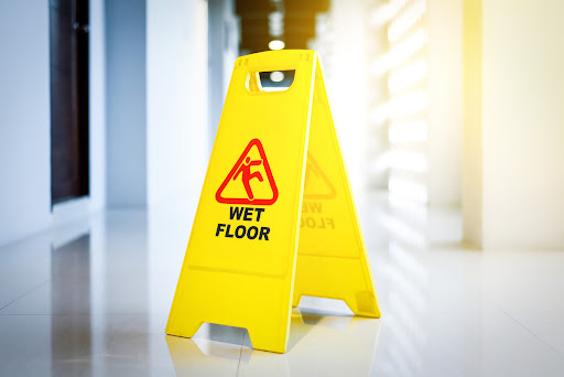 A yellow wet floor sign in a spacious white hallway