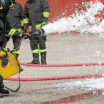 firefighter extinguishing with foam the car after road accident