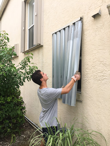 A young man seals the windows of a house before a hurricane.