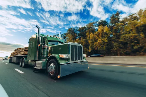 A green 18-wheeler carrying a load of plywood.