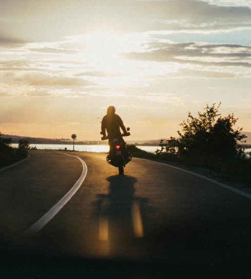 A person riding a motorcycle on a road at sunset