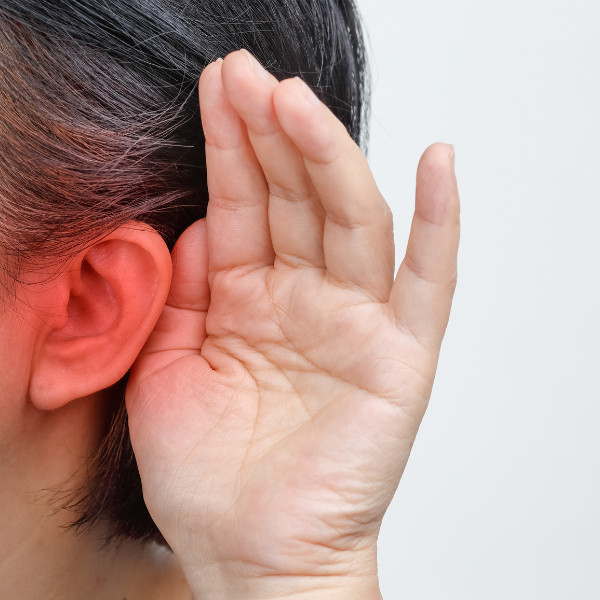 A person holds their hand to their ear after suffering hearing loss.