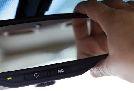 A hand adjusting the rearview mirror of a car