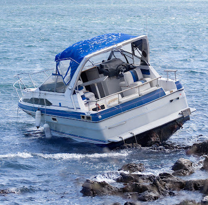 A blue and white boat stuck on rocks near the shore