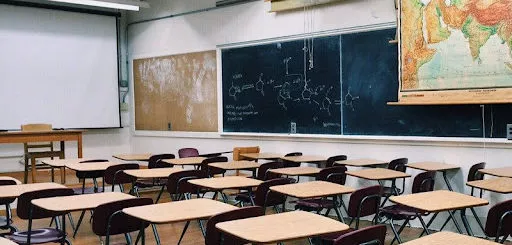 A classroom with desks, chalkboards, and a map