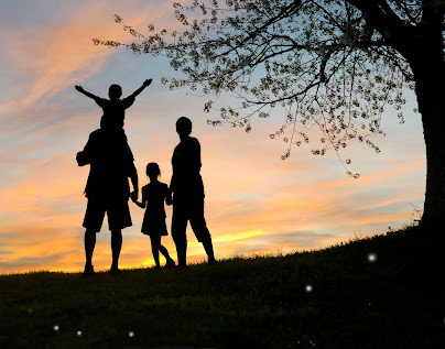 A family walking together next to a tree at sunset